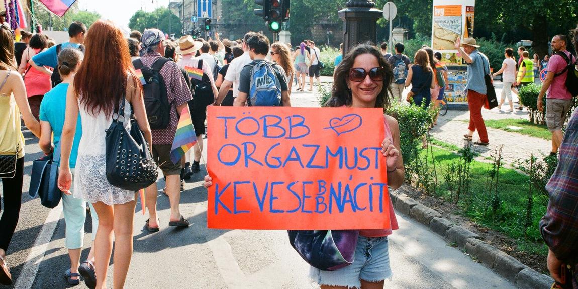 Nainen pitää kylttiä Pride mielenosoituksessa. Kyltissä lukee unkariksi "Enemmän orgasmeja, vähemmän natseja".