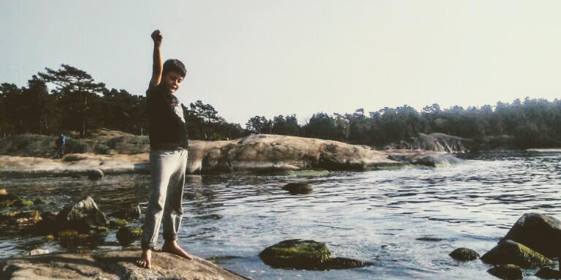 Poika seisoo kivellä meren äärellä nyrkki pystyssä.