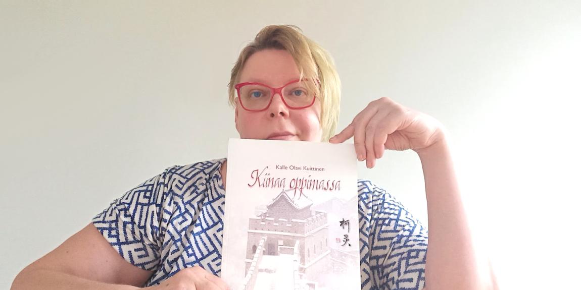 Tiina Sandberg pitää edessään Kalle Kuittisen "Kiinaa oppimassa" kirjaa.