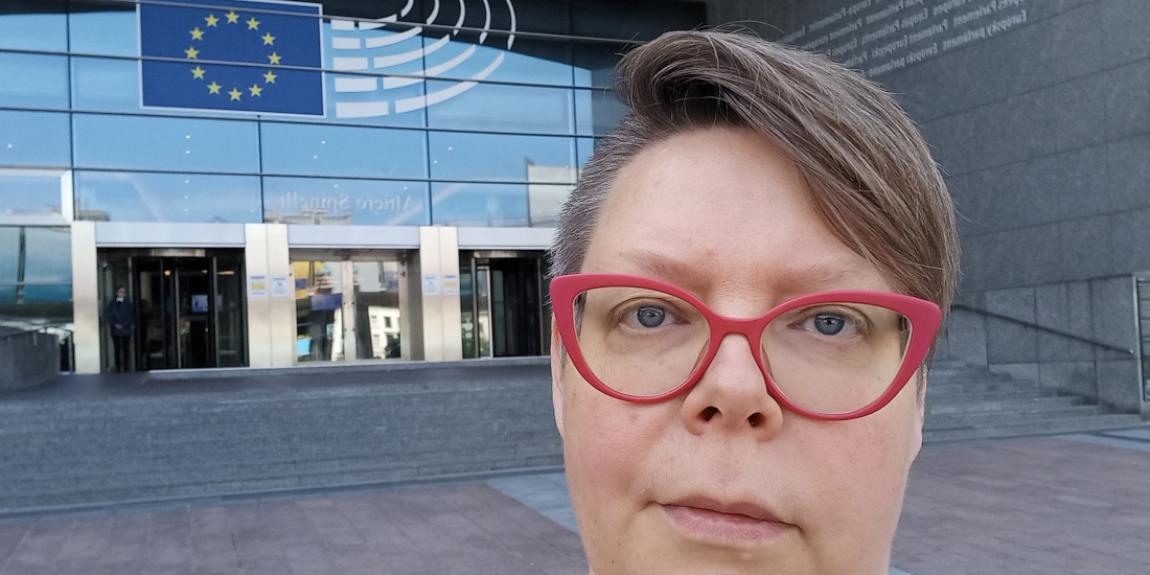 Tiina Sandberg seisoo EU-parlamentin oven edessä.
