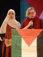 Tiina Sandberg pitää puheenvuoroa Palestiinan lippujen keskellä.