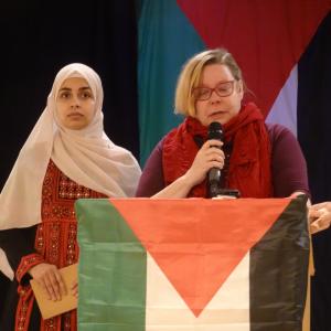 Tiina Sandberg pitää puheenvuoroa Palestiinan lippujen keskellä.