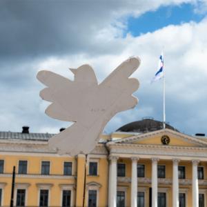 Kuvassa pahvinen rauhankyyhky taustanaan Helsingin yliopisto.