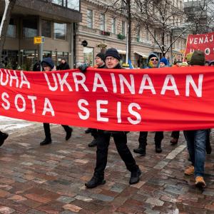 Ihmiset kantavat banderollia, jossa lukee Rauha Ukrainaan, sota seis.