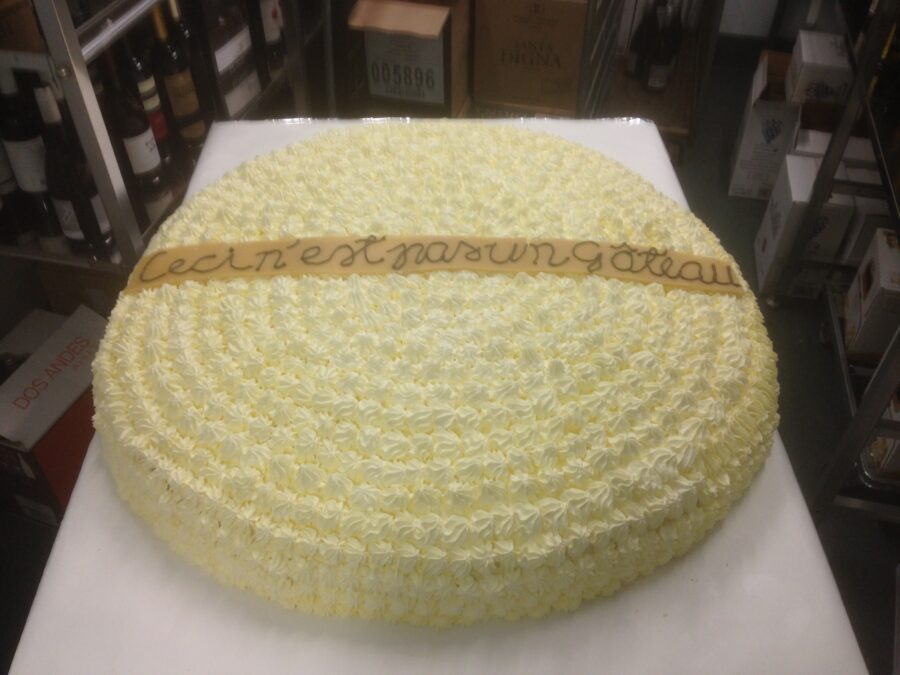 Kermakakussa lukee ”Ceci n'est pas un Gâteau” Tämä ei ole kakku – yhtä vähän piippu tai mitään muutakaan kuin inhorealistinen melkein kaurismäkinen fakta