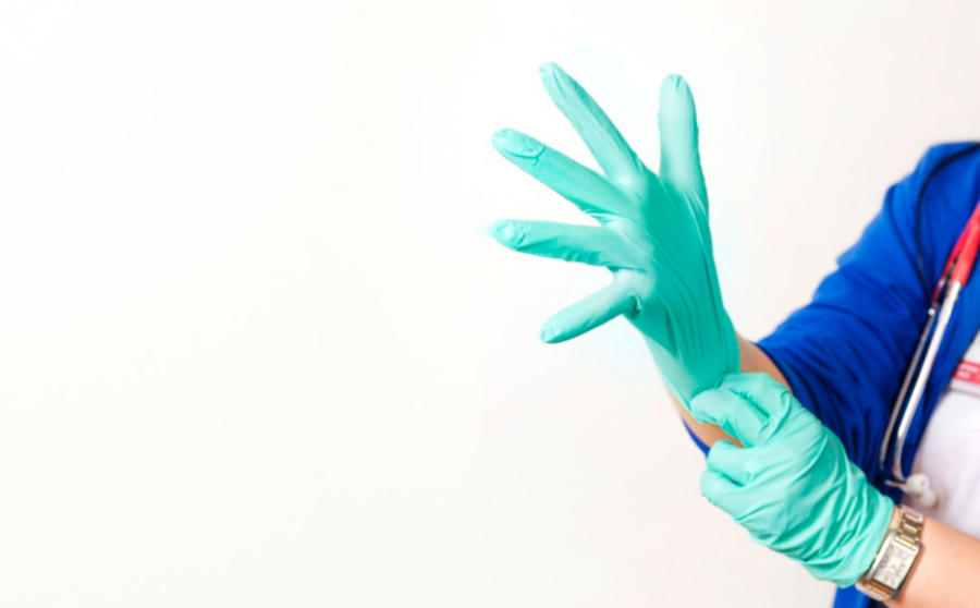 Hoitaja vetää suojahanskat käteen.