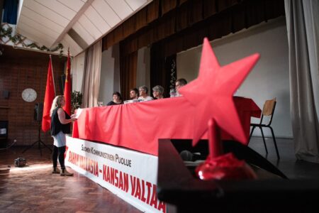 SKP:n edustajakokouksen puheenjohtajisto kuvattuna punatähden takaa.