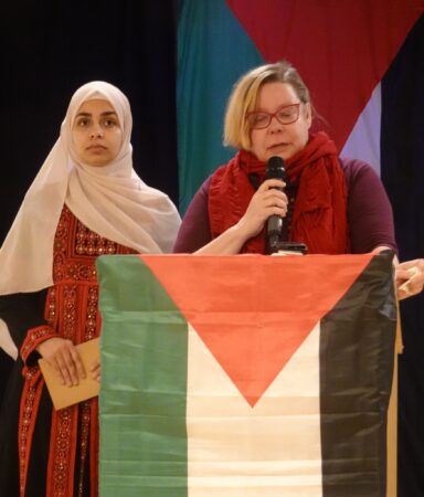 Tiina Sandberg pitää puheenvuoroa Palestiinan lippujen keskellä.