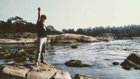 Poika seisoo kivellä meren äärellä nyrkki pystyssä.