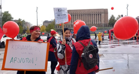 JHL:n jäsenet pitävät mielenosoituksessa kylttiä