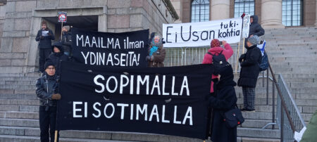 Ihmisiä banderollien kanssa Eduskuntatalon portailla. "Ei USA:n tukikohtia"