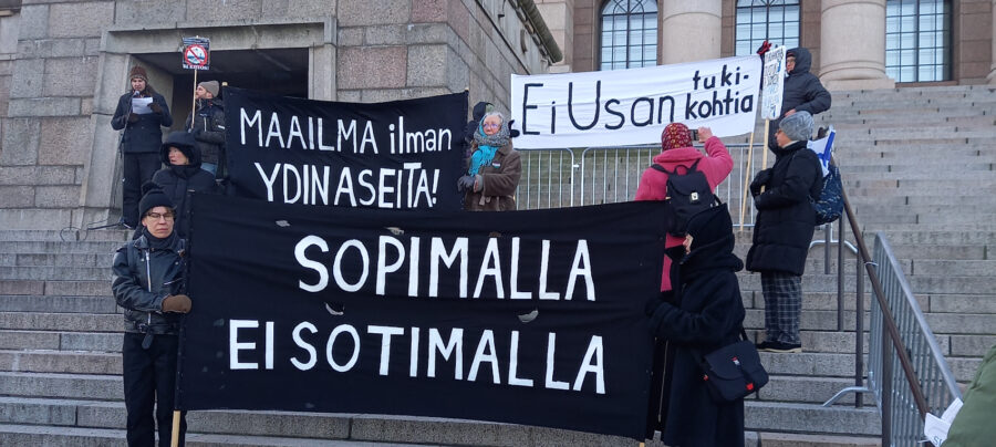 Ihmisiä banderollien kanssa Eduskuntatalon portailla. "Ei USA:n tukikohtia"