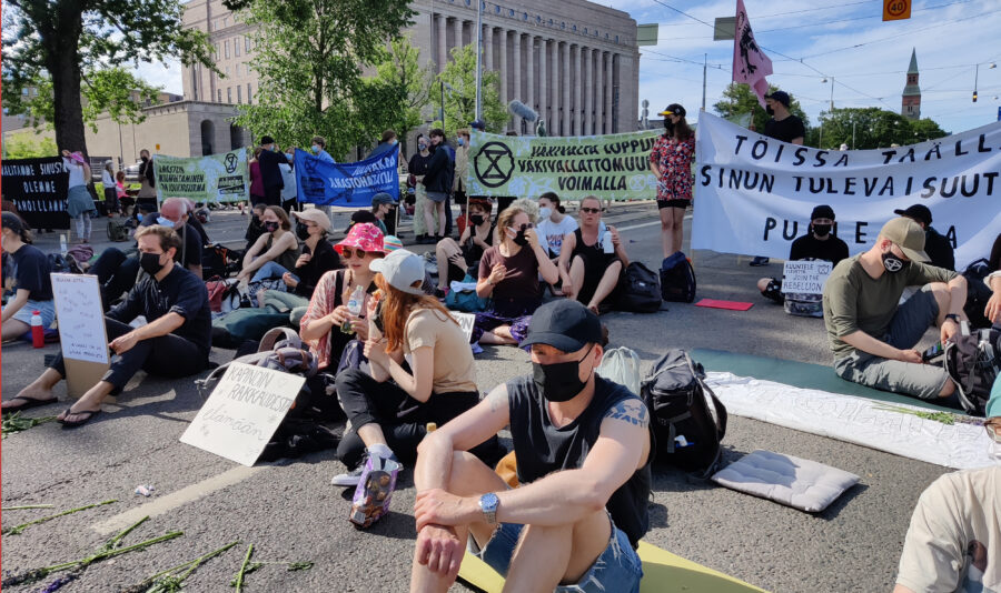 Elokapinalaiset istuvat tiellä Eduskunnan edessä.