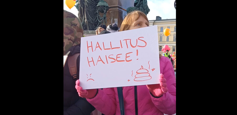 Kuvassa nainen pitää kylttiä