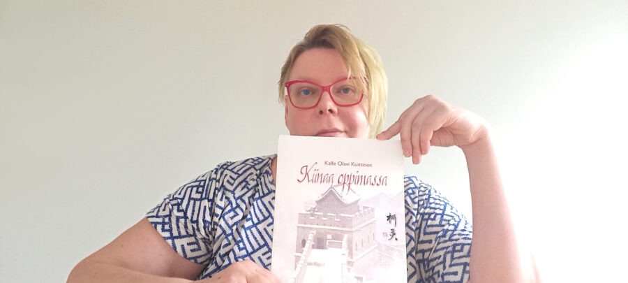 Tiina Sandberg pitää edessään Kalle Kuittisen "Kiinaa oppimassa" kirjaa.