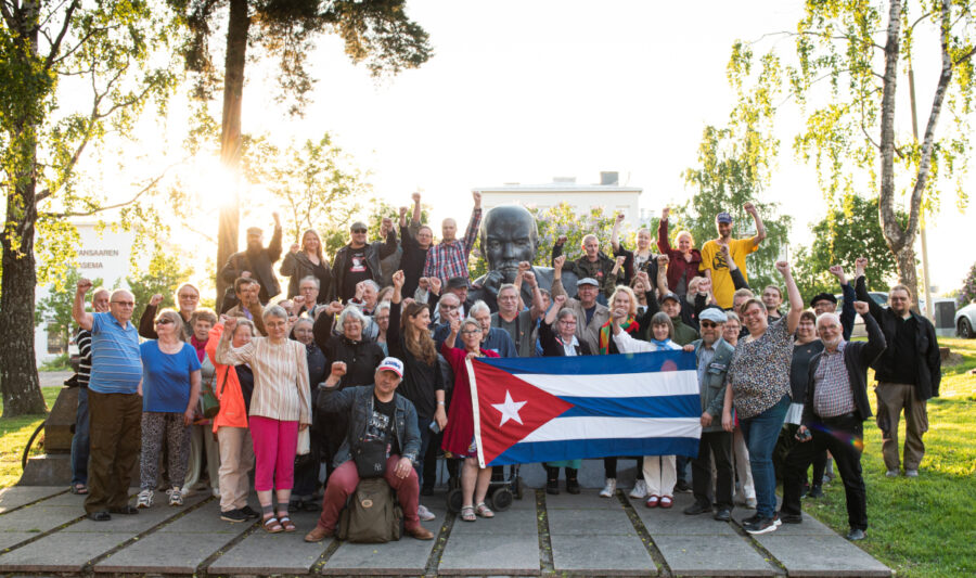 Joukko SKP:n jäseniä poseeraa Kotkassa yhdessä Leninin patsaan kanssa.