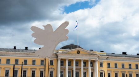 Kuvassa pahvinen rauhankyyhky taustanaan Helsingin yliopisto.