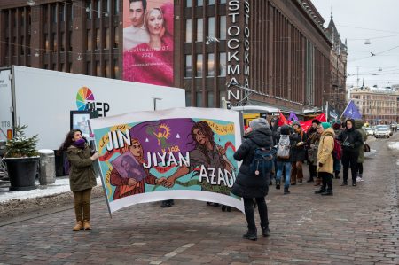 Naistenpäivän marssin keulassa banderolli Iranin vapausliikkeen teksteillä "Jin, jiyan, azadi - Nainen, elämä, vapaus".