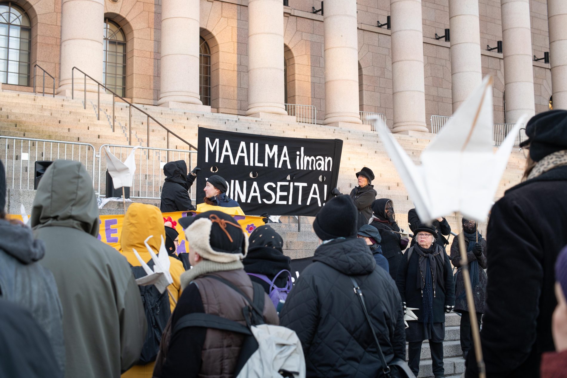 Ydinaseiden vastaisia mielenosoittajia eduskuntatalon edustalla, portailla pidetään banderollia, jossa lukee "Maailma ilman ydinaseita".